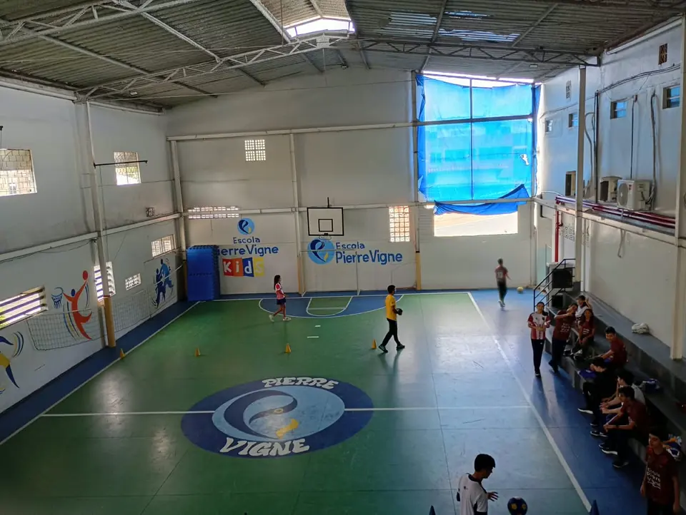 Quadra poliesportiva coberta da escola com o logotipo Pierre Vigne no piso
