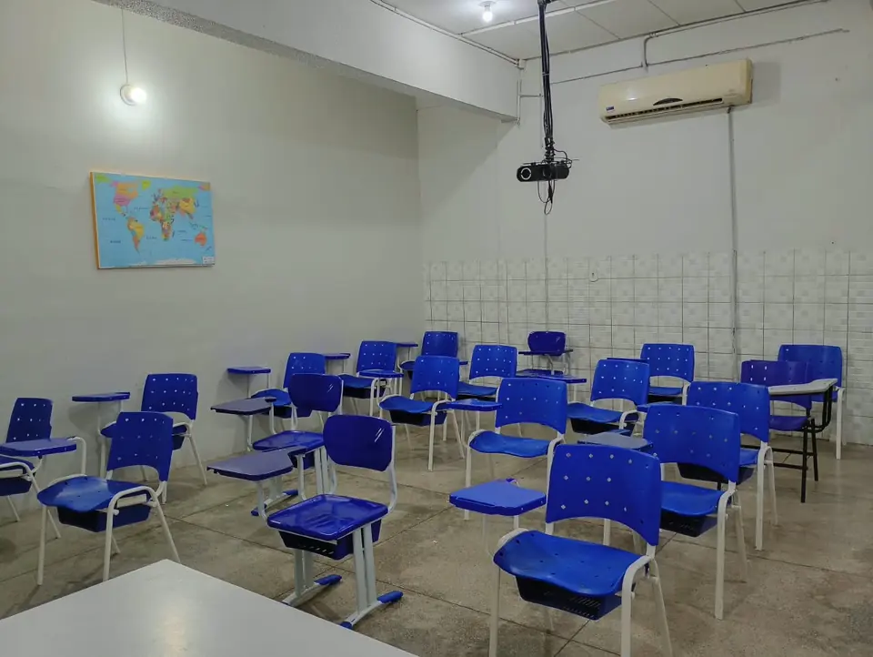 Sala de aula com carteiras azuis e mapa-múndi na parede